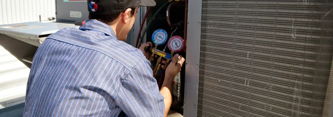 HVAC technician servicing a condenser unit in Giddings