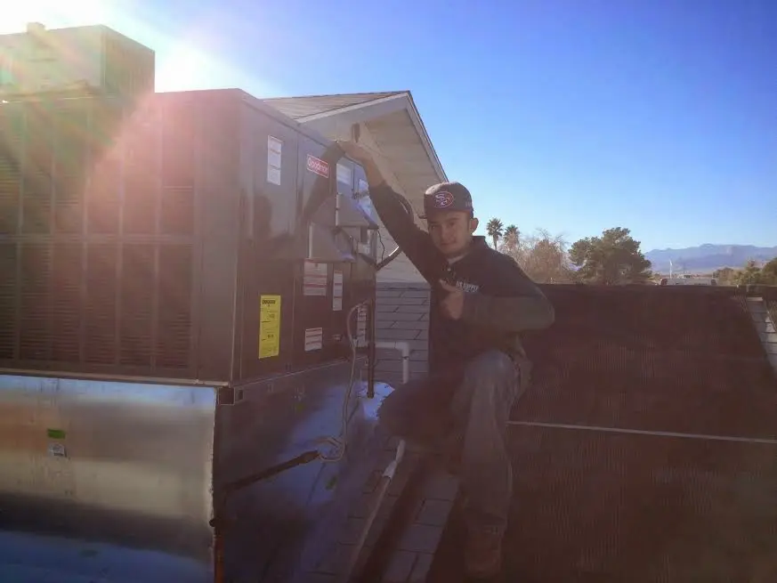HVAC technician performing Air Duct Cleaning on a rooftop unit in Giddings
